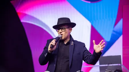 Fusion Events game show host on stage with a microphone, leading a live interactive show at a corporate conference