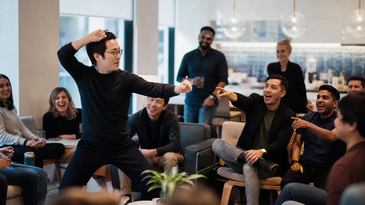 Team member acting out a charades clue for laughing colleagues