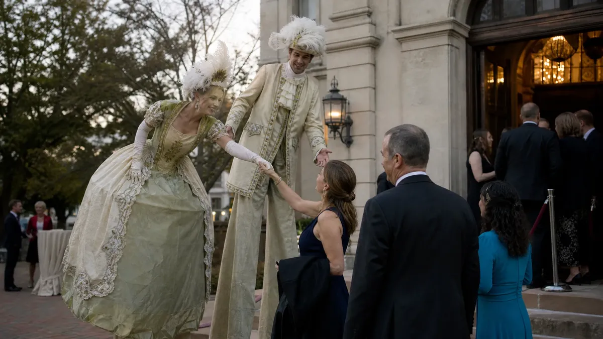 Stilt walkers in elegant costume greeting guests at an event entrance