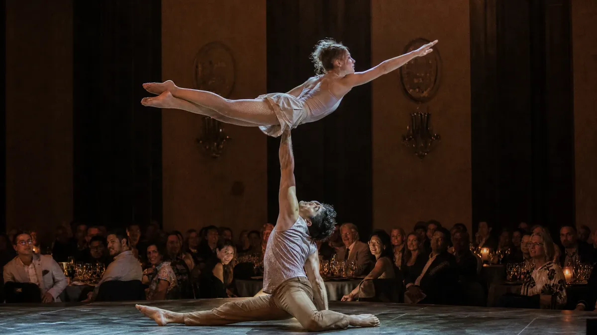 Cirque-style acrobatic duo performing a balance act on a gala stage