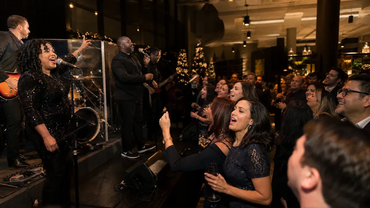 Live band performing at a company holiday party with guests singing along