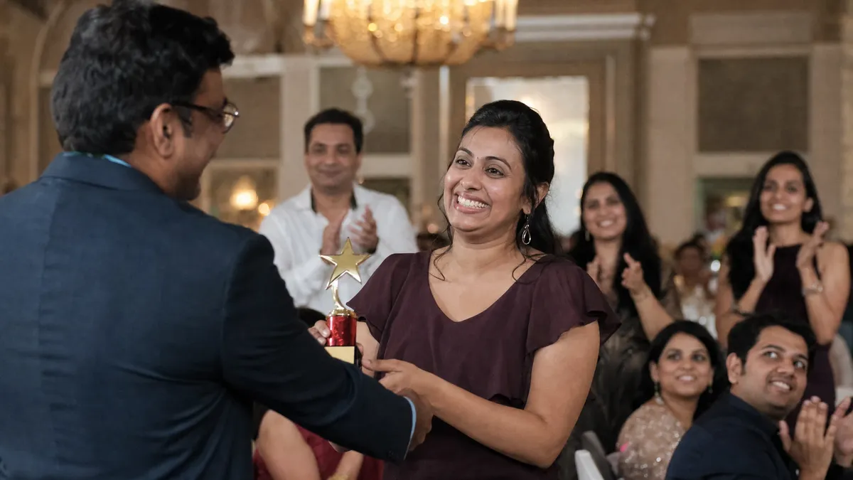 Employee accepting an award to applause at a company holiday party