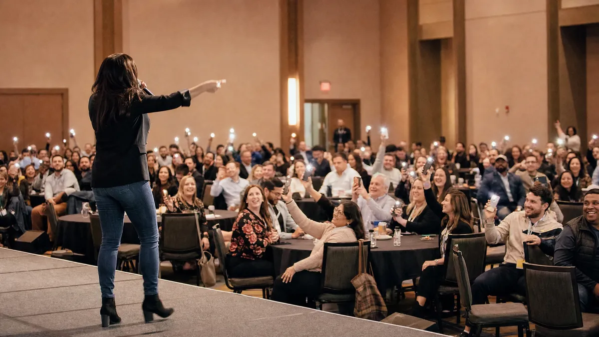 Hosted corporate game show with employee teams voting on their phones in a ballroom