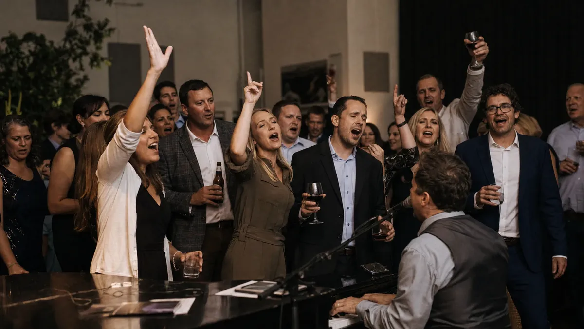 Guests singing along around dueling pianos with drinks raised