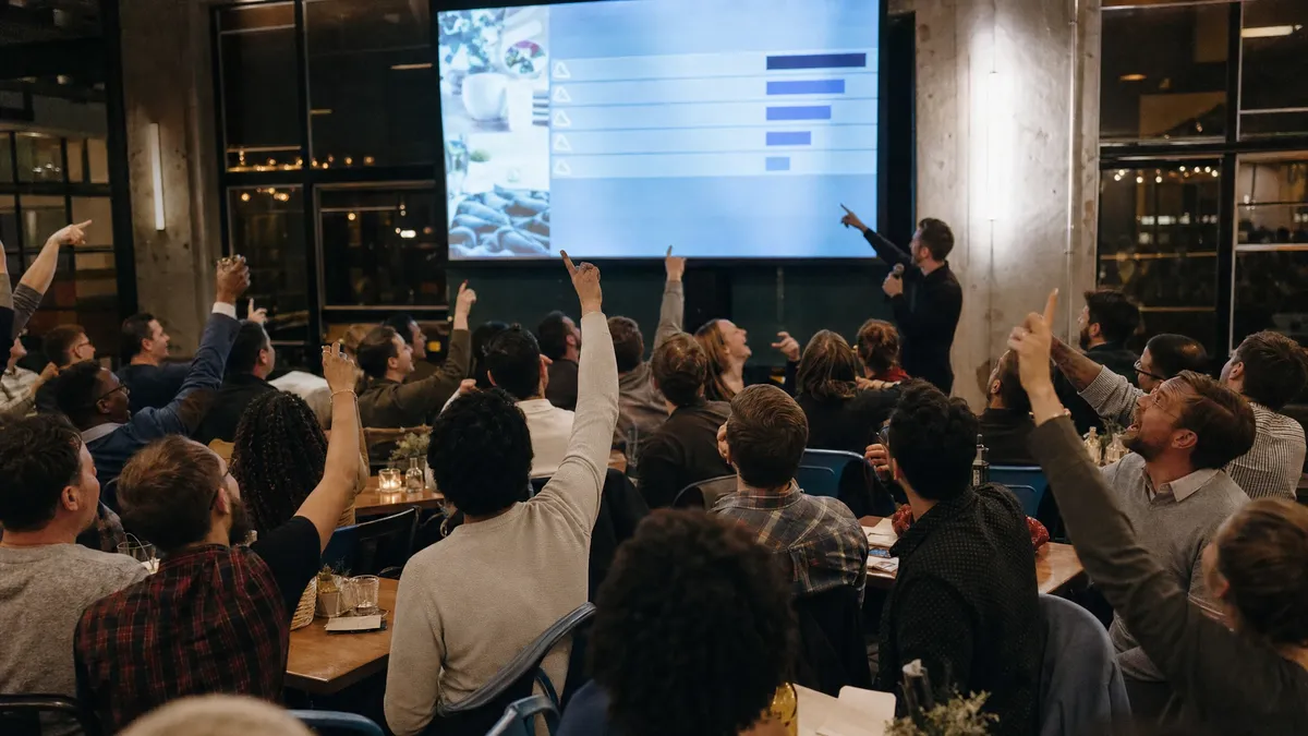 Employees shouting survey answers at a big screen during a company party