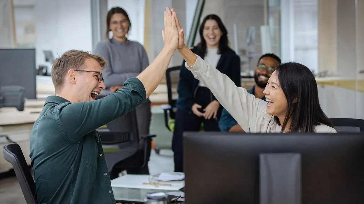 Coworkers high-fiving during a lighthearted office icebreaker