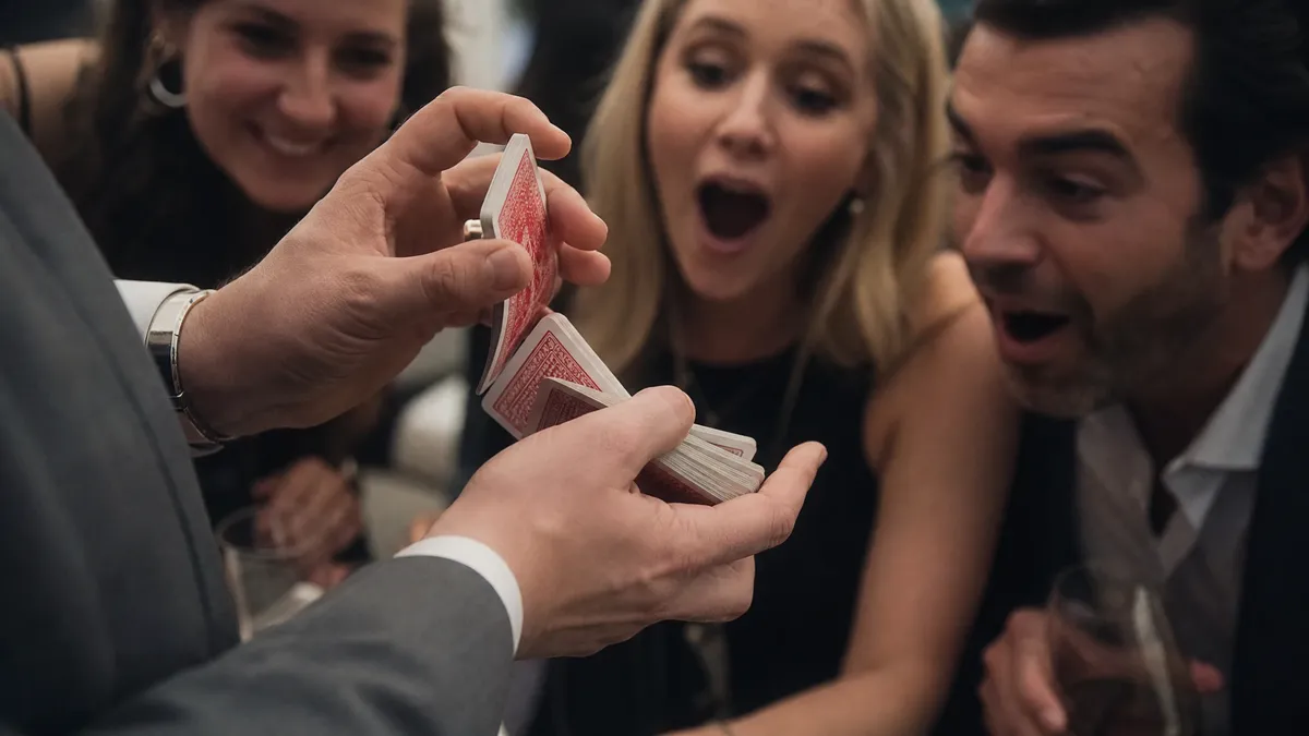 Magician mid card flourish with astonished guests leaning in