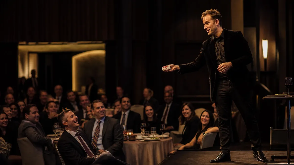 Stage magician performing for a seated corporate audience in a ballroom