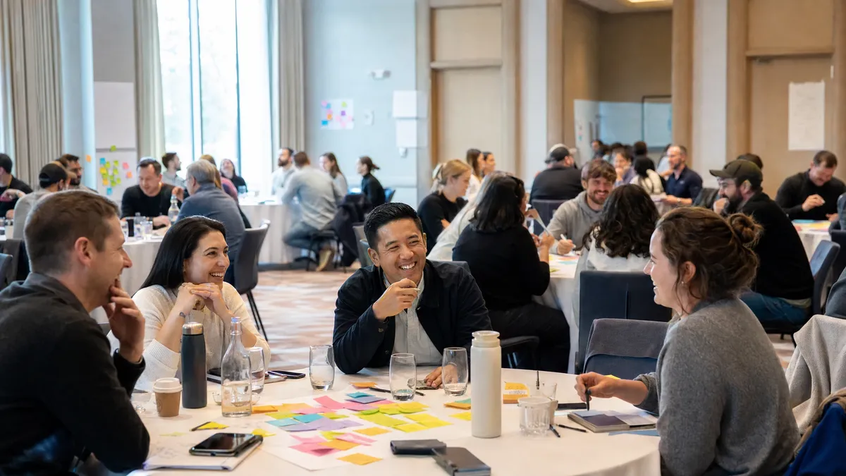 Team offsite groups collaborating with sticky notes during a work icebreaker