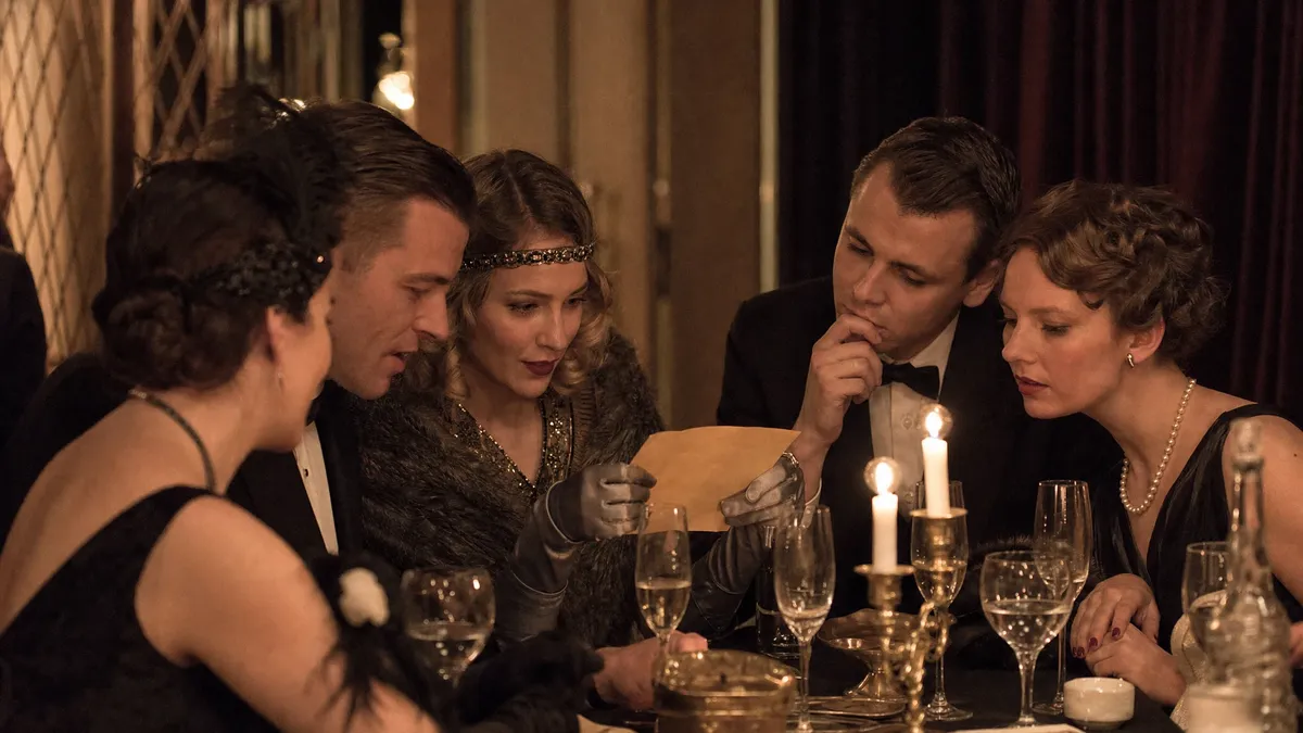 Dinner party guests inspecting a vintage clue envelope by candlelight