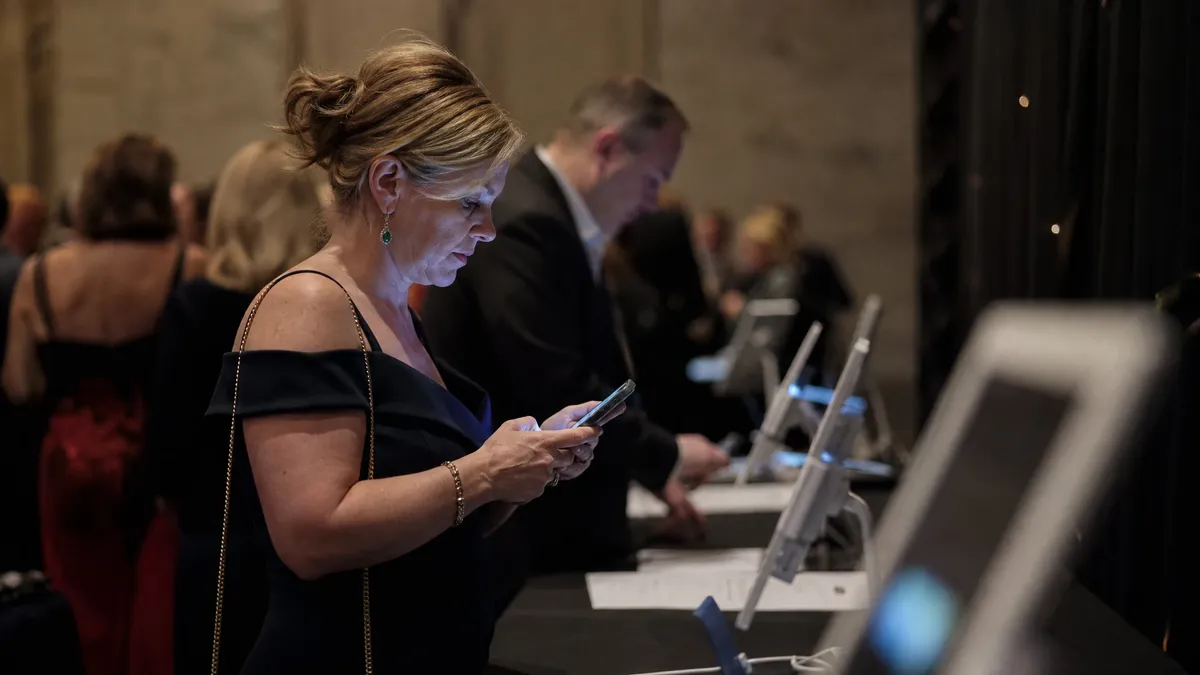 Guest placing a mobile bid on a phone at a silent auction station