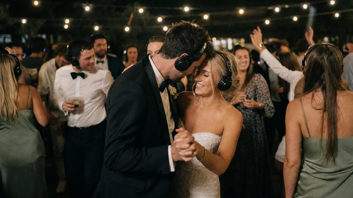 Bride and groom dancing at a wedding silent disco under string lights