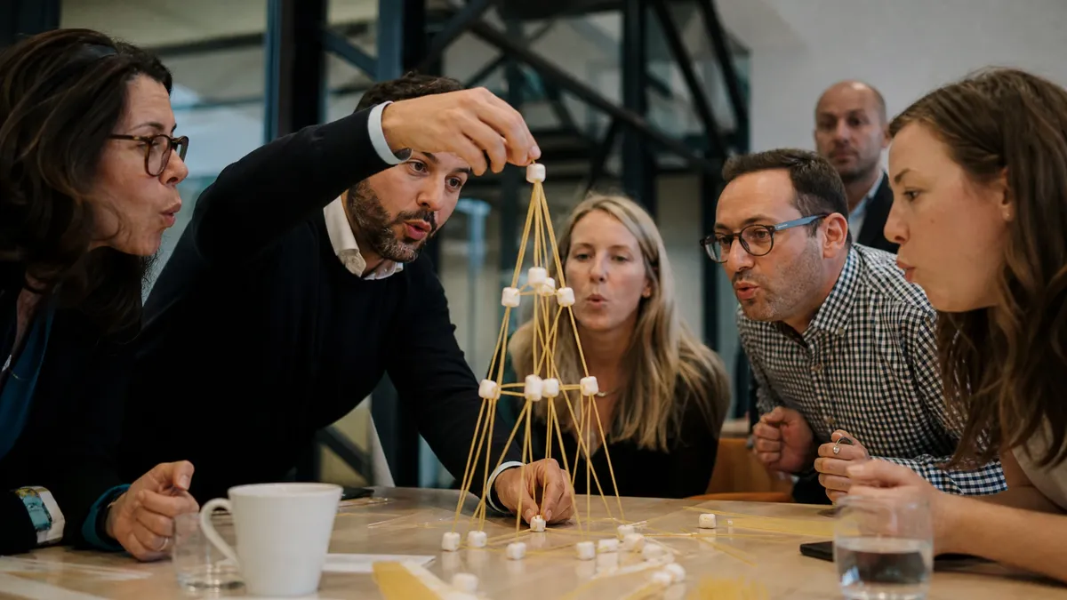 Team building a spaghetti and marshmallow tower together at the office