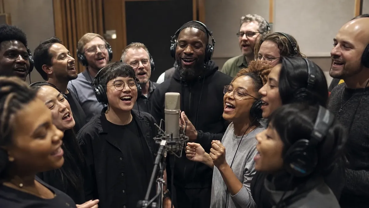 Employees recording a team anthem together in a music studio session