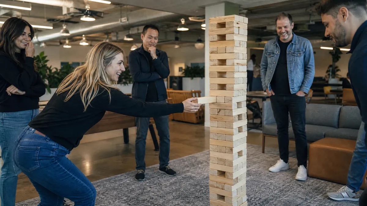 Team playing giant jenga in an office lounge during a team building game