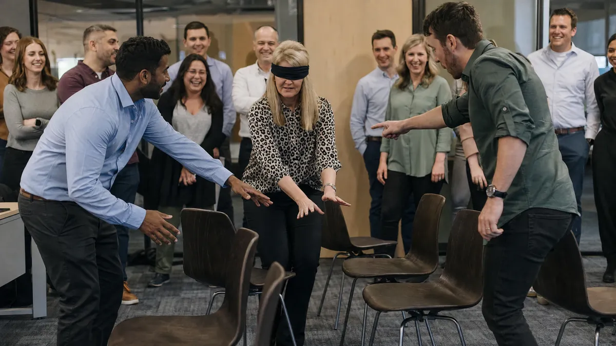 Blindfolded colleague guided through an obstacle course by teammates