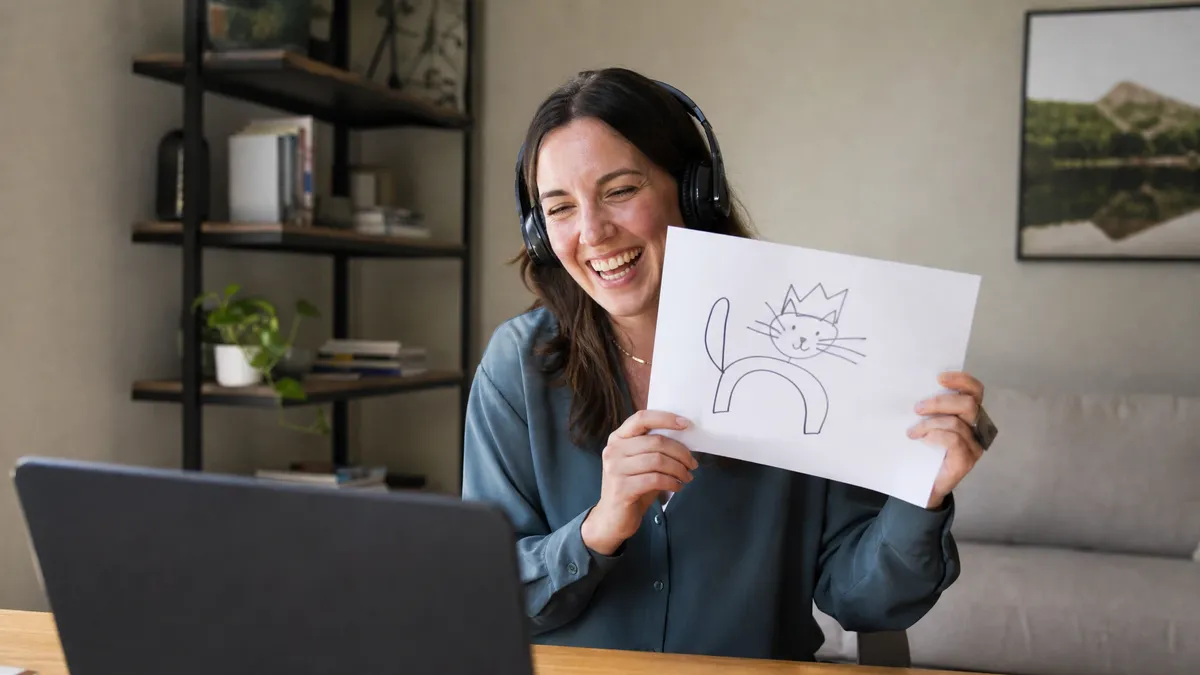 Remote worker holding a drawing up to the webcam during a virtual team game