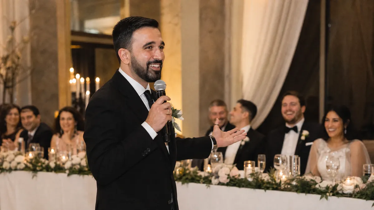 Wedding MC with a microphone commanding a reception as guests laugh