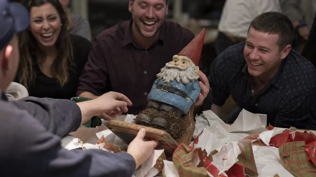 Coworker unwrapping a hilariously odd white elephant gift