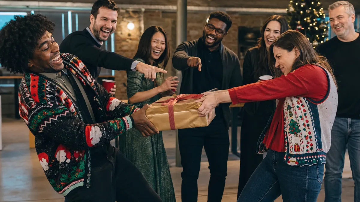 Two coworkers in a playful tug-of-war over a coveted white elephant gift