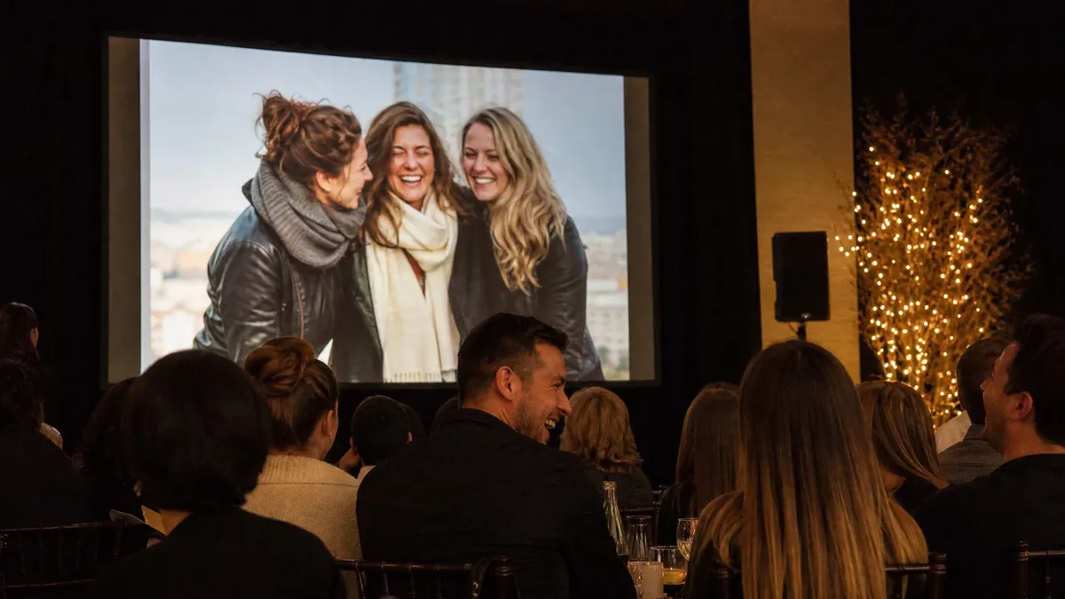 Employees laughing at a year-in-review slideshow at a company party