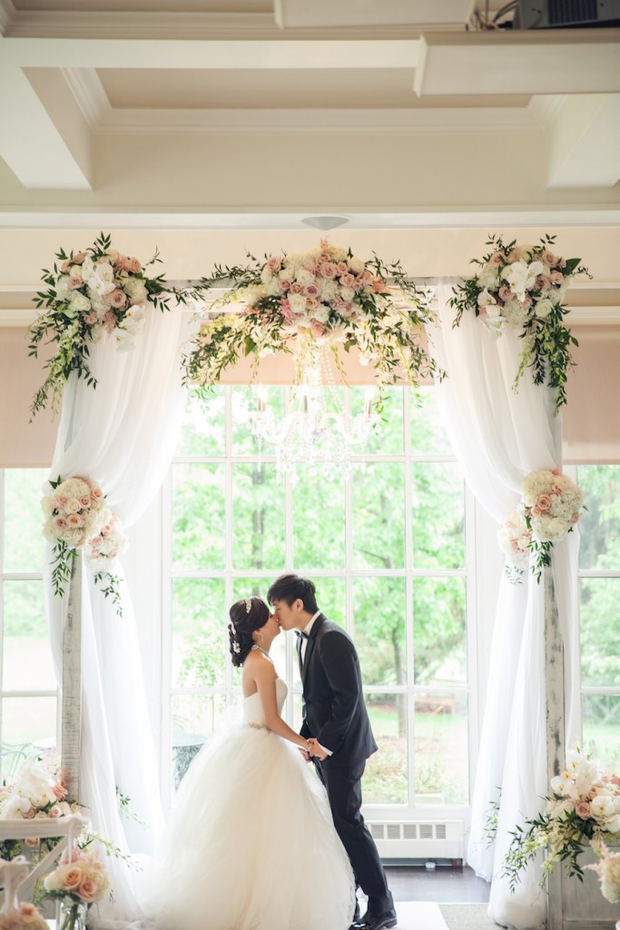bride and groom kissing under ceremony canopy